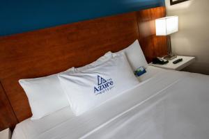 uma cama com almofadas brancas com um sinal de Nike em The Azure Hotel em Mesa