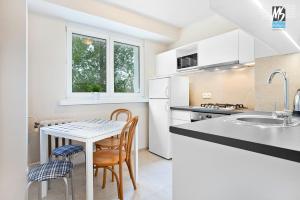 - une cuisine avec des placards blancs, une table et des chaises dans l'établissement MS Apartments Antica, à Gdynia
