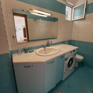 a bathroom with a sink and a washing machine at Villa Lori in Qeparo