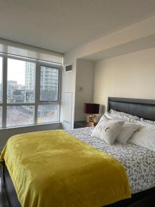 a bedroom with a large bed with a yellow blanket at Toronto Downtown Luxurious Stylish 3 Bedroom 3 Bath 2 Balconies near Rogers Centre lakeview condo in Toronto