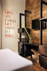 a bedroom with a desk and a television on a brick wall at Relais Orso in Rome