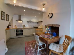 uma cozinha com uma mesa de madeira e uma lareira em St Etheldreda's Cottage, Wells, Somerset em Wells