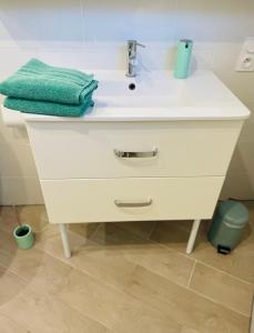 a white bathroom sink with a green towel on it at Charmant Studio proche Lac et Forêt in Carcassonne