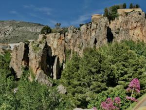 a rocky mountain with trees and pink flowers at CA LIDIA - Apartamentos Turisticos EL BALCONET in Benimantell