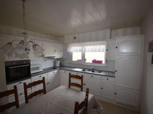 a kitchen with white cabinets and a table and chairs at Serene Holiday Home in Peer in Peer