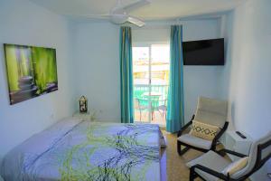 sypialnia z łóżkiem i krzesłem oraz balkon w obiekcie LOFT - GARAJE - TERRAZA PRIVADA Junto al Parque y Playa w mieście Conil de la Frontera