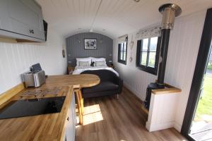 una cocina y una sala de estar con una cama en una casa pequeña en Springwood Shepherd Huts Glamping York, en York