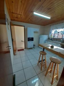 a kitchen with a table and two stools at chales e aptos Carvalhos em monte verde in Monte Verde