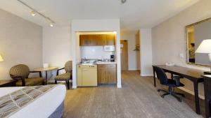 a hotel room with a bed and a desk and a kitchen at Dilworth Inn in Kelowna