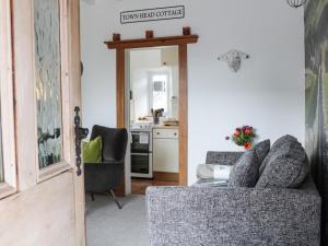 a living room with a couch and a kitchen at Town Head Cottage in Skipton