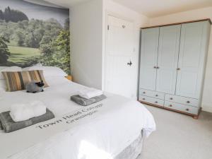 a bedroom with a white bed with a painting on the wall at Town Head Cottage in Skipton