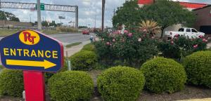 a sign for an entrance in front of bushes at Raintree Inn and Suites in Houston +2 photos