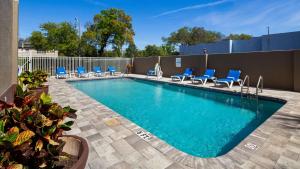 a swimming pool with blue lounge chairs and a pool at Best Western Tampa in Tampa