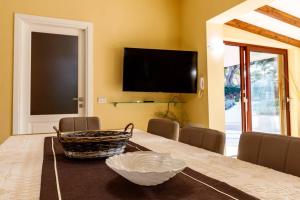 a dining room with a table with a television on the wall at Villa Fenicottero in Porto Pino