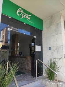 a store front with a green sign on a building at Hotel Oscar Econômico Montes Claros in Montes Claros +130 photos