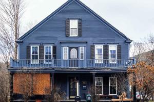 ein blaues Haus mit Balkon darüber in der Unterkunft River Moon Retreat - Historic House with 8 Bedrooms, Hot Tub, On The River, High Speed WiFi 