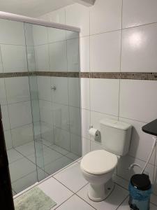 a bathroom with a toilet and a glass shower at Pousada Villa Galinhos in Galinhos