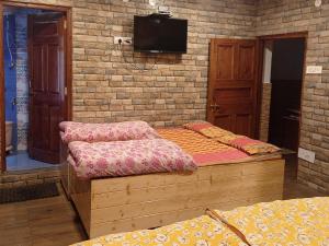 a bedroom with a bed and a tv on a brick wall at Mehdudia Guest House in Shimla