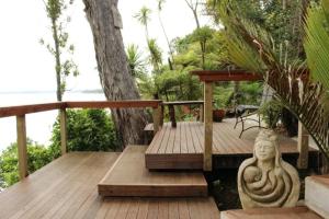 a wooden deck with a statue of a buddha at Neptune Coastal Haven in Auckland