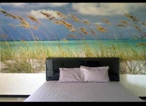 um quarto com uma cama com uma pintura da praia em D'SAWAH GUESTHOUSE em Klaten