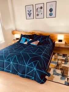 een slaapkamer met een bed met een blauw dekbed en 2 lampen bij Apartamento zona colonial lindísimo 202 in Zipaquirá