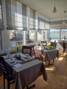 a dining room with tables and chairs and windows at Hotel Logis Beauséjour in Erquy