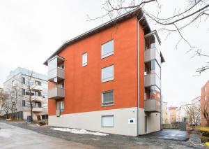 ein orangefarbenes und weißes Apartmenthaus auf einer Straße in der Unterkunft Hiisi Homes Tampere Armonkallio in Tampere