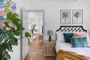 a bedroom with a bed with blue and pink pillows at Tropicana Bungalow - Retro Getaway in Cairns North