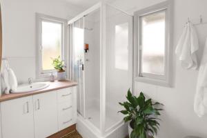 a white bathroom with a shower and a sink at Tropicana Bungalow - Retro Getaway in Cairns North +13 photos