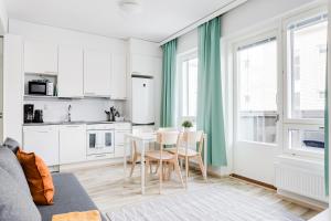 eine Küche mit weißen Schränken sowie einem Tisch und Stühlen in der Unterkunft Hiisi Homes Tampere Armonkallio in Tampere