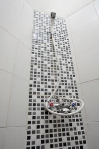 a shower with a hose on a black and white tile floor at D'Paragon Trikora in Palembang