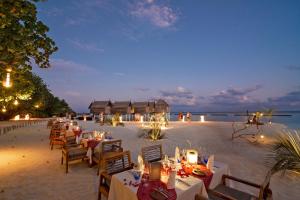 a beach with tables, chairs and umbrellas at Constance Moofushi Maldives - All Inclusive in Himandhoo 