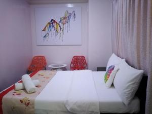 a bedroom with a bed and two red chairs at HalfWay House Hostel Mactan Cebu Airport in Mactan