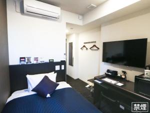 Habitación de hotel con cama y TV de pantalla plana. en HOTEL LiVEMAX Yokohama Stadium Mae, en Yokohama