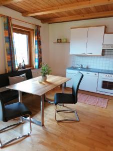 a kitchen with a wooden table and two chairs at Apartments Scherer in Obertilliach