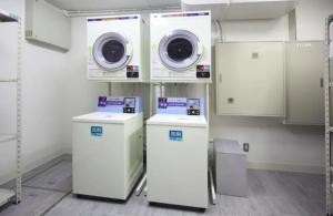 a laundry room with two washer and dryers at Exsasion Sugamo in Tokyo