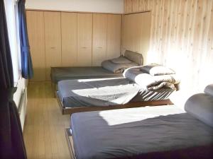 três camas sentadas num quarto com uma janela em Pension Yu em Ebetsu