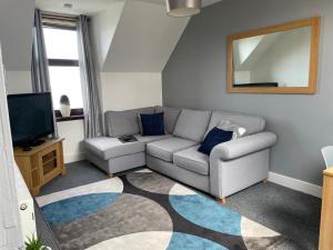 uma sala de estar com um sofá e uma televisão em Skerry View - Overlooking the Moray Firth - close to Beaches, Harbour, Shops and Restaurants em Lossiemouth