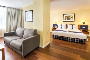 a hotel room with a bed and a chair at Holiday Inn Lisbon by IHG in Lisbon