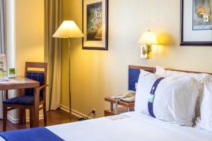 a hotel room with a bed and a desk and a lamp at Holiday Inn Lisbon by IHG in Lisbon