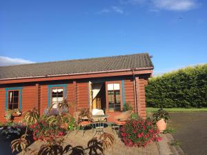 uma cabana de madeira com uma mesa e cadeiras à sua frente em Balnabrechan Lodge em Arbroath