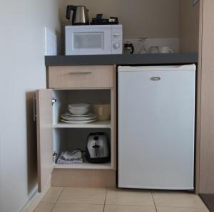 a kitchen with a white refrigerator and a microwave at Bella Vista Motel Kaikoura in Kaikoura