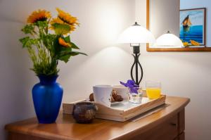 un tavolo con un vaso di fiori e un vaso di succo d'arancia di Apartment & Rooms Graciela a Rovigno (Rovinj)