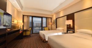 a hotel room with two beds and a flat screen tv at Jinling Hotel Beijing in Beijing