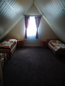 a attic room with two beds and a window at Domek Tosia in Bukowiec