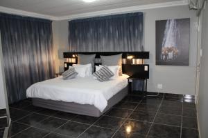 a bedroom with a large bed with white sheets and pillows at El Gran Chaparral Guest House in Pretoria