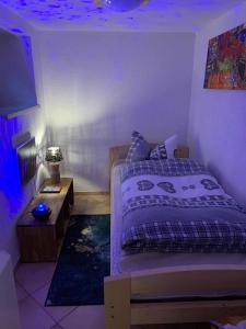 een slaapkamer met een bed en een tafel met een blauw licht bij Berghaus Carlsfeld in Eibenstock