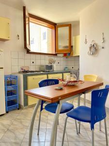 uma cozinha com uma mesa de madeira e cadeiras azuis em Marettimo Appartamenti em Marettimo