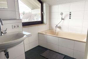 a white bathroom with a sink and a bath tub at Ferienwohnung in Laichingen-Feldstetten in Laichingen