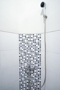 ducha con azulejos blancos y negros en D'Paragon Kijang Utara en Alastuwo